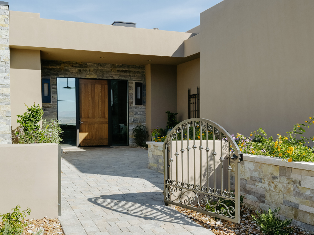 A charming entryway and courtyard scene, with a wooden door, decorative gate, and a flower bed.